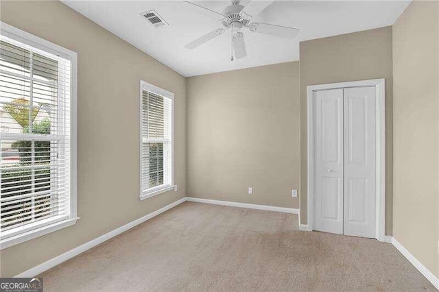 unfurnished bedroom featuring a closet, light colored carpet, and ceiling fan