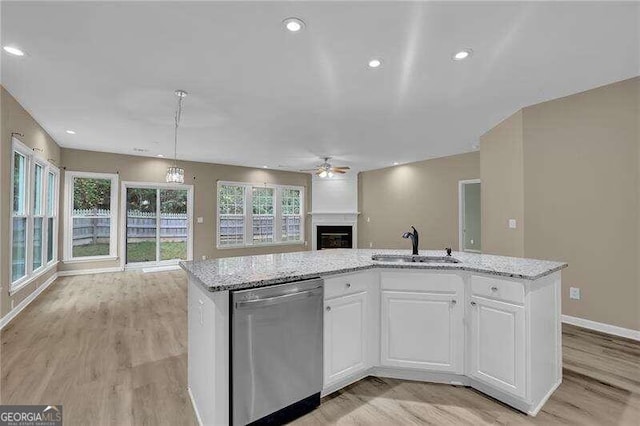 kitchen with light hardwood / wood-style flooring, stainless steel dishwasher, a center island with sink, and white cabinets