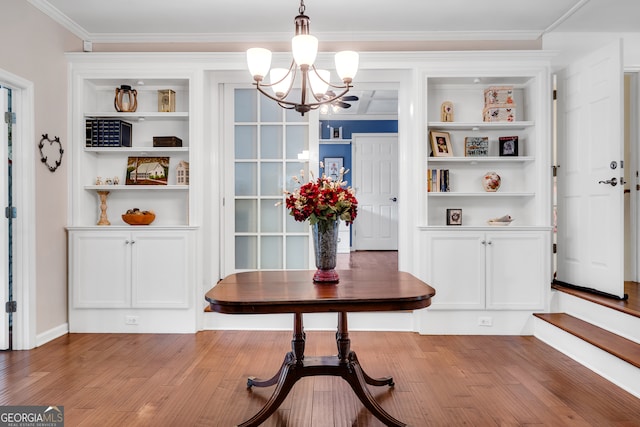 dining room with ornamental molding, hardwood / wood-style floors, and an inviting chandelier