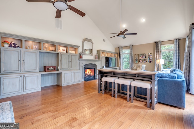 living room featuring ceiling fan, light hardwood / wood-style flooring, and high vaulted ceiling