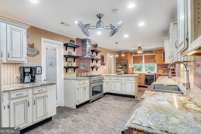 kitchen with sink, kitchen peninsula, beverage cooler, high end range, and pendant lighting