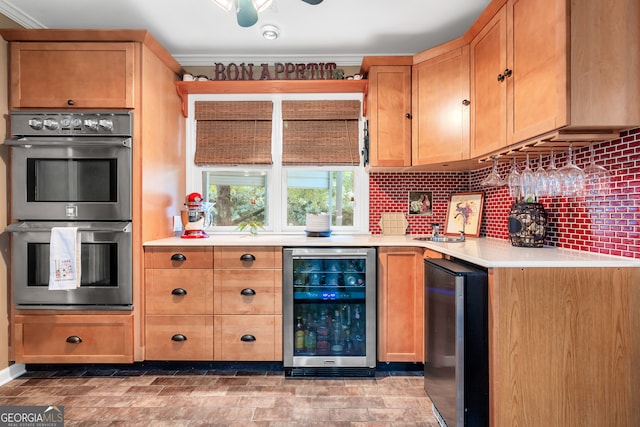 kitchen featuring black fridge, beverage cooler, tasteful backsplash, stainless steel double oven, and crown molding