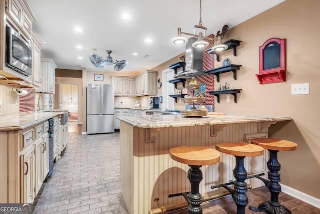 kitchen with stainless steel appliances, cream cabinets, crown molding, and a breakfast bar