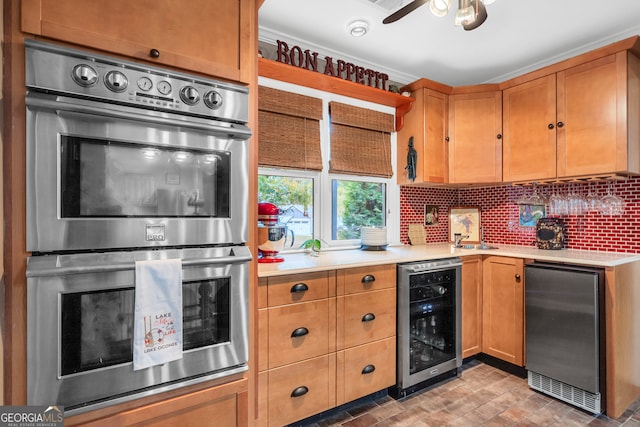 kitchen with beverage cooler, decorative backsplash, ceiling fan, and stainless steel appliances