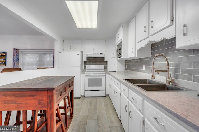 kitchen with white cabinetry, sink, white appliances, light wood-type flooring, and decorative backsplash