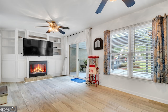 living room with ceiling fan, built in features, and light wood-type flooring