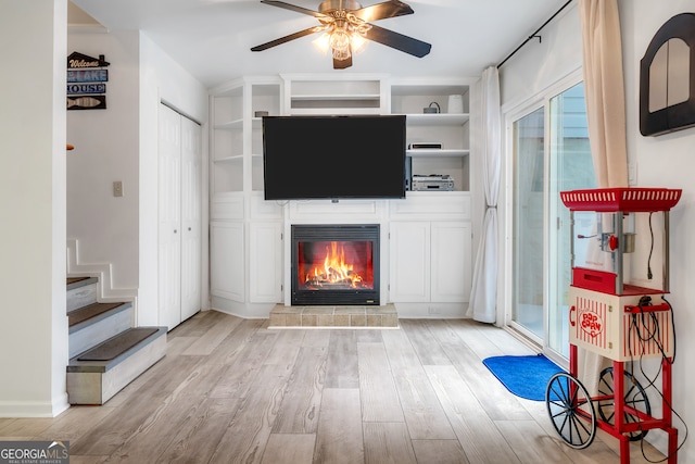 unfurnished living room with a tiled fireplace, ceiling fan, and light hardwood / wood-style flooring