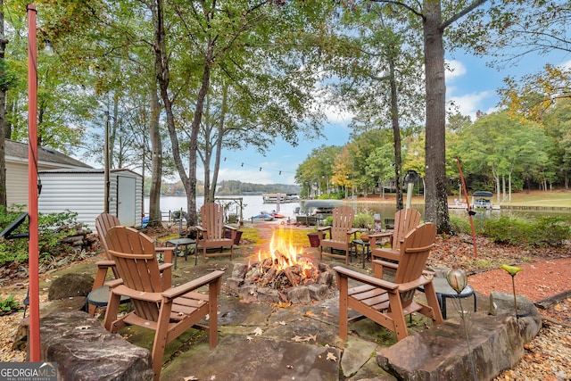 view of patio with a storage shed, a fire pit, and a water view