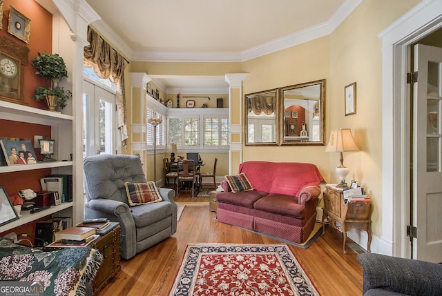 living area with crown molding, light wood-type flooring, and decorative columns