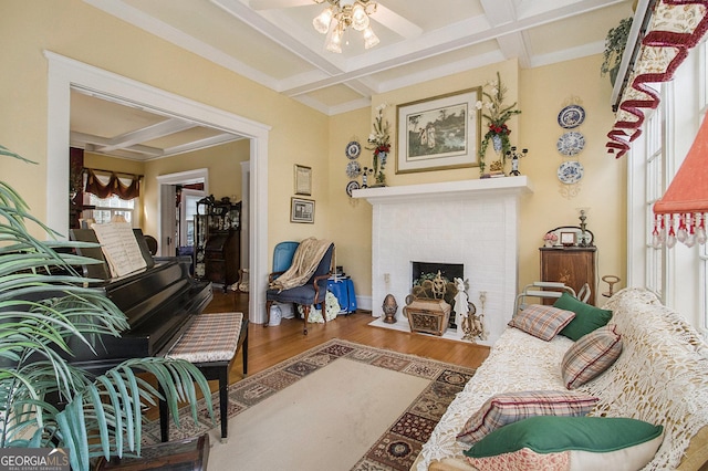 living room with ceiling fan, coffered ceiling, wood finished floors, baseboards, and a brick fireplace