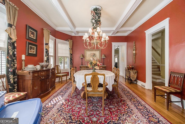 dining room with light wood-style flooring, coffered ceiling, stairs, beamed ceiling, and an inviting chandelier