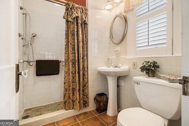 bathroom featuring toilet, a stall shower, tile walls, and tile patterned floors