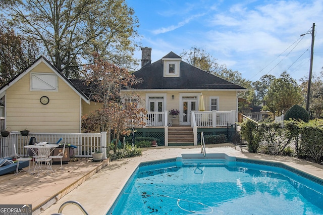 exterior space with a fenced in pool, an outbuilding, french doors, and a wooden deck