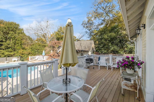 wooden terrace featuring outdoor dining area and a fenced in pool