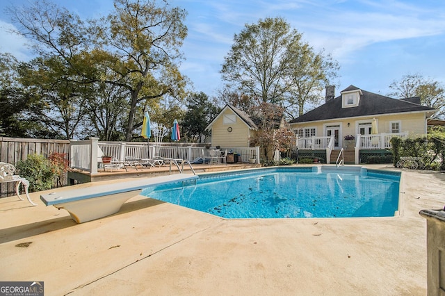 view of pool with a fenced in pool, a patio area, fence, a deck, and a diving board