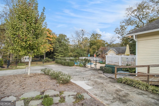 view of yard with a deck, fence, and an outdoor pool