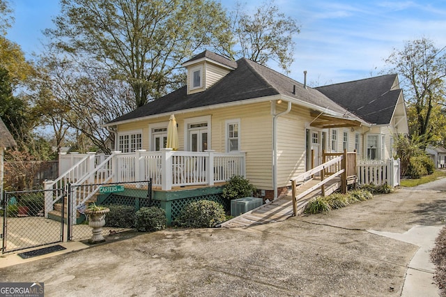 bungalow featuring a deck, central AC, a shingled roof, french doors, and a gate