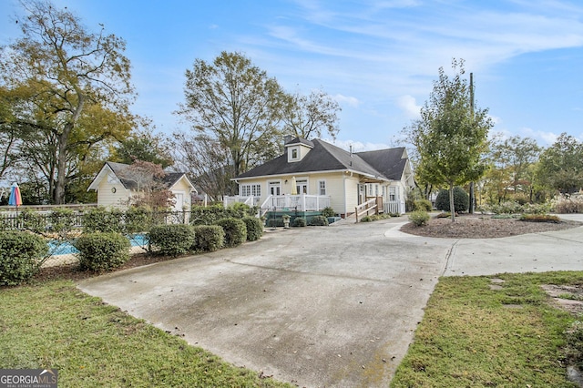 view of front facade featuring concrete driveway and fence