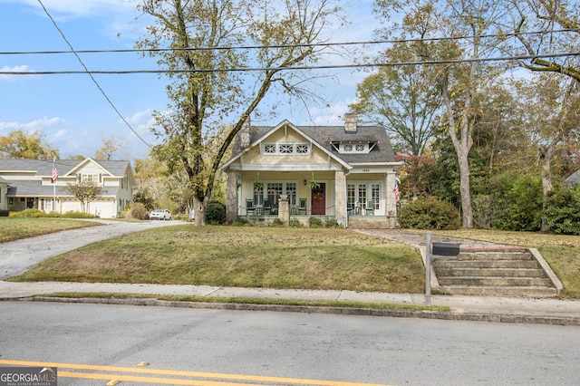 view of front of home featuring a porch, a chimney, and a front yard