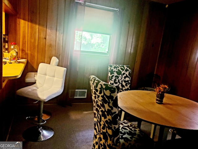 dining room with wooden walls, carpet flooring, and visible vents