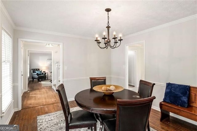 dining room with an inviting chandelier, hardwood / wood-style floors, and ornamental molding