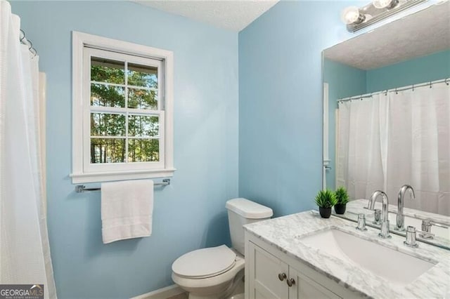 bathroom featuring vanity, a textured ceiling, and toilet