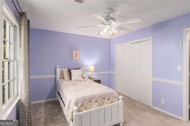 bedroom with light colored carpet, ceiling fan, and a closet