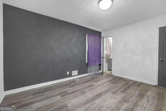2611 Kings Cir, Lawrenceville, GA 30044 - unfurnished bedroom featuring wood finished floors, a textured ceiling, and baseboards