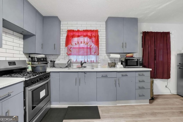 2611 Kings Cir, Lawrenceville, GA 30044 - kitchen featuring appliances with stainless steel finishes, gray cabinets, a sink, light wood-style floors, and a textured ceiling
