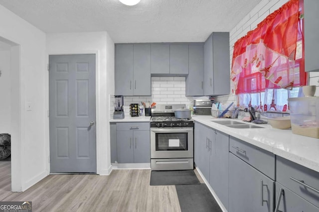 2611 Kings Cir, Lawrenceville, GA 30044 - kitchen featuring gray cabinetry, stainless steel gas range oven, a sink, light wood-type flooring, and a textured ceiling