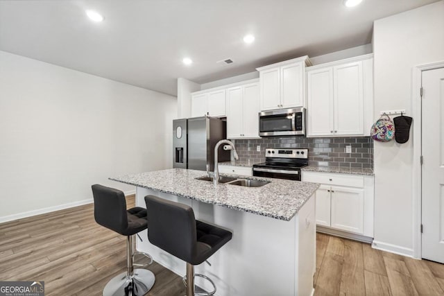 kitchen with light hardwood / wood-style floors, white cabinetry, sink, and appliances with stainless steel finishes