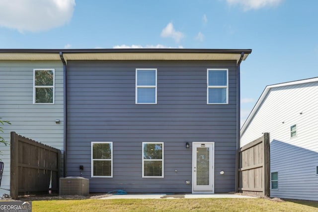 back of property with central AC unit and a lawn