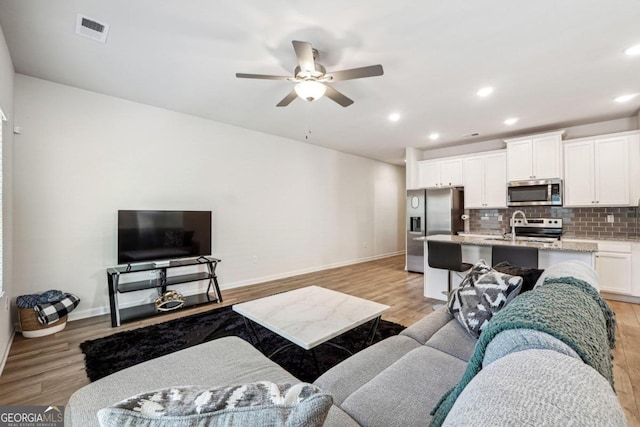 living room featuring ceiling fan and light wood-type flooring