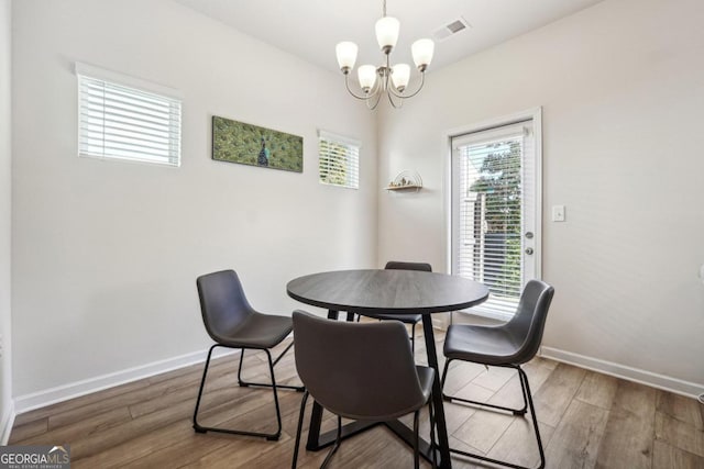 dining space with wood-type flooring and an inviting chandelier