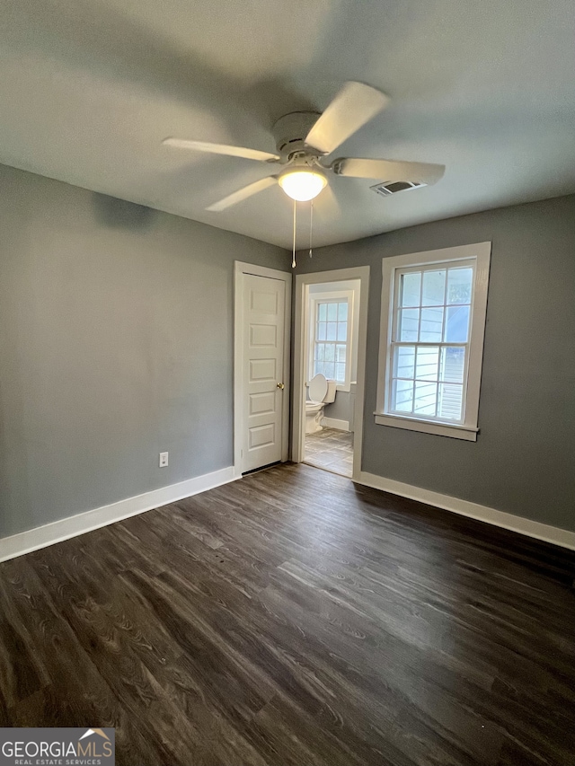 unfurnished bedroom with ceiling fan, ensuite bath, and dark hardwood / wood-style flooring