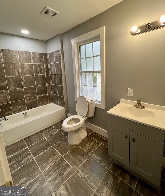 full bathroom featuring vanity, tiled shower / bath, and toilet