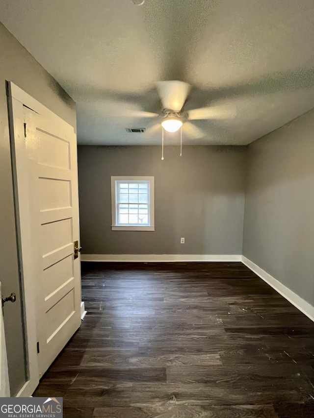 empty room featuring dark hardwood / wood-style flooring, ceiling fan, and a textured ceiling