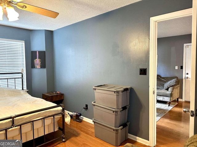 bedroom with a textured ceiling, wood-type flooring, and ceiling fan