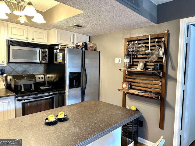 kitchen featuring backsplash, white cabinets, a textured ceiling, and stainless steel appliances