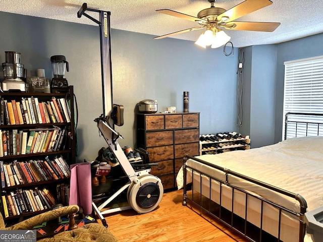 bedroom featuring light hardwood / wood-style floors, ceiling fan, and a textured ceiling