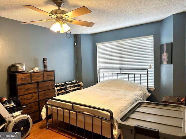 bedroom featuring hardwood / wood-style floors, ceiling fan, and a textured ceiling