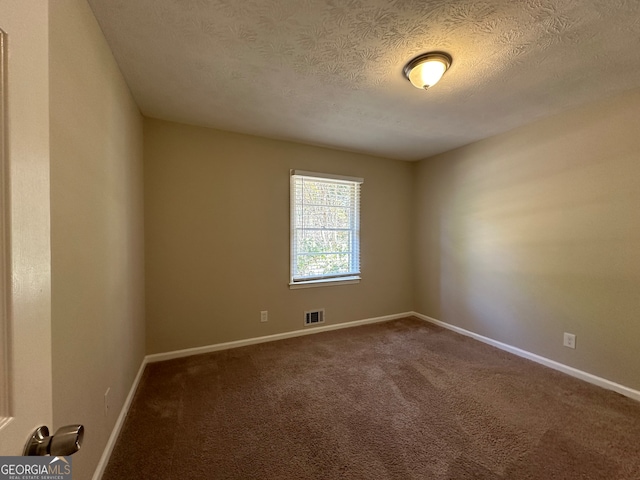 empty room with carpet and a textured ceiling