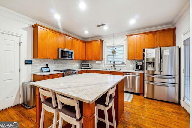 kitchen featuring a kitchen breakfast bar, stainless steel appliances, a kitchen island, and light wood-type flooring