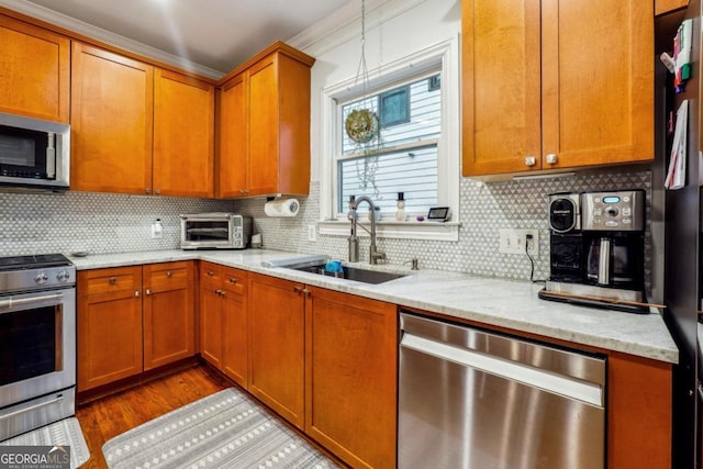 kitchen with stainless steel appliances, light stone countertops, decorative backsplash, sink, and light hardwood / wood-style floors