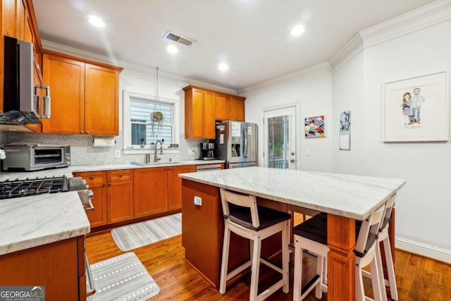 kitchen featuring stainless steel refrigerator with ice dispenser, sink, a kitchen island, and a breakfast bar