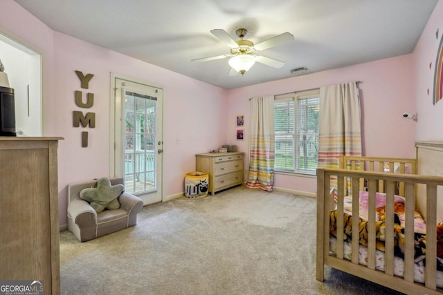 carpeted bedroom featuring access to outside, ceiling fan, and a crib