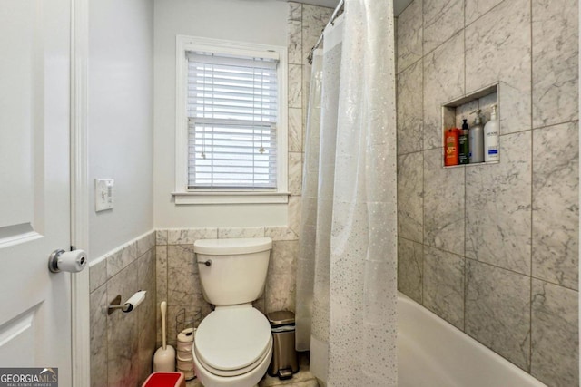 bathroom featuring tile walls, shower / bath combination with curtain, and toilet