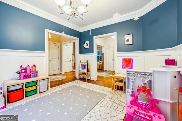 game room featuring an inviting chandelier, hardwood / wood-style floors, and crown molding