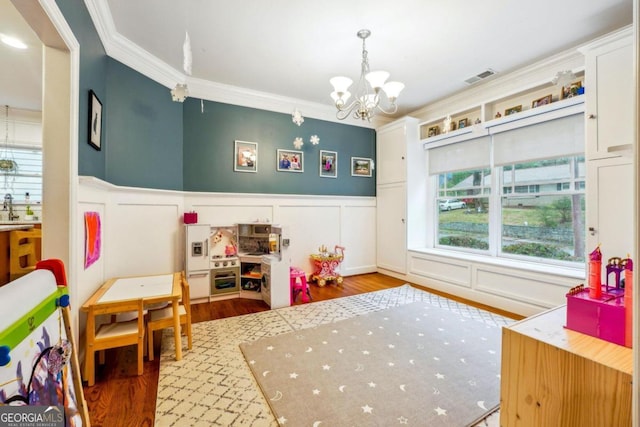 playroom featuring hardwood / wood-style floors, a chandelier, and crown molding