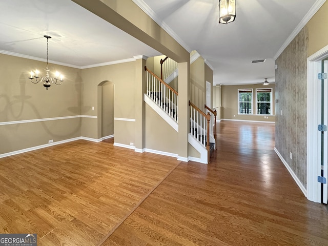 entrance foyer with hardwood / wood-style flooring, crown molding, and an inviting chandelier